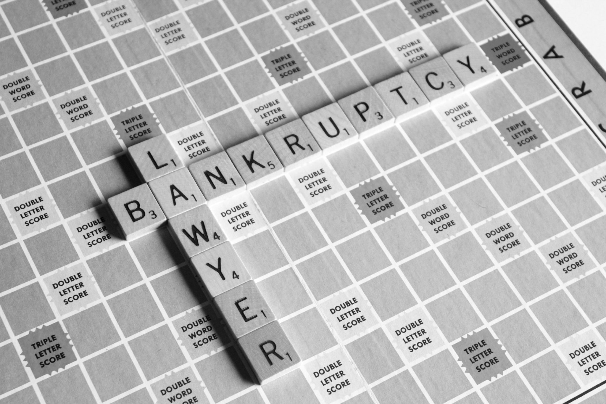 "Scrabble board with tiles forming the words 'Bankruptcy' and 'Lawyer' on a game board, symbolizing the essential role of a bankruptcy lawyer in managing debt relief, financial restructuring, and legal advice for individuals and businesses facing insolvency."