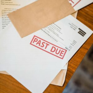 Close-up view of past due notices, unpaid invoices, and overdue bills scattered on a table, indicating financial distress, creditor pressure, and the consideration of filing for bankruptcy protection or seeking debt relief services to stop collections and lawsuits.